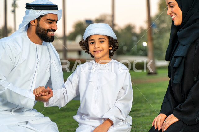 عائله عربيه إماراتيه  خليجيه مكونه من ثلاث أفراد, قضاء وقت ممتع في الحديقه, ايماءات وجه تدل على السعادة , النظر الى بعضهم البعض بكل حب ,  رحله عائليه في يوم مشمس, مفهوم الأسره السعيده, إجازه صيفيه, الاستمتاع باللعب الجماعي في المنتزه, تسليه وترفيه, عطلة ن