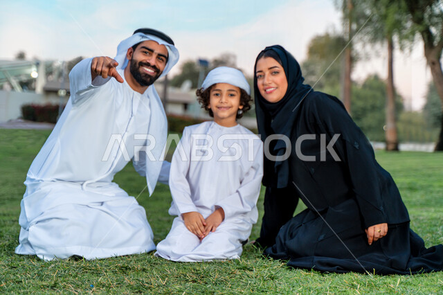 عائله عربيه إماراتيه  خليجيه مكونه من ثلاث أفراد, قضاء وقت ممتع في الحديقه, الإشارة الى شيء ما, رحله عائليه في يوم مشمس, مفهوم الأسره السعيده, إجازه صيفيه, الاستمتاع باللعب الجماعي في المنتزه, تسليه وترفيه, عطلة نهاية الاسبوع