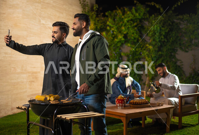 مجموعة من الشباب العرب الخليجيين السعوديين يقضون أوقات ممتعة في إحدى الشاليهات السياحية بالسعودية، اصدقاء يقيمون حفلة شواء، التقاط صور السيلفي التذكارية من خلال الهاتف المحمول، أجواء شتوية، جلسة وناسة وتعارف، إجتماع الأصدقاء، سهرة شبابية