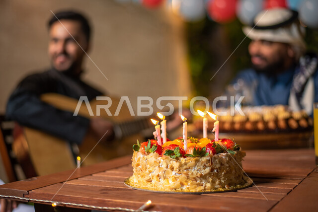 مجموعة من الشباب العرب الخليجيين السعوديين يقضون أوقات ممتعة في إحدى الشاليهات السياحية بالسعودية، الاحتفال بعيد الميلاد، أعياد ومناسبات سعيدة، كيكة عيد الميلاد، شاب يعزف على آلة القيثارة، أجواء شتوية، جلسة وناسة وتعارف، إجتماع الأصدقاء، سهرة شبابية