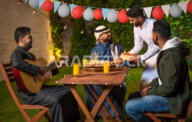 شاب يقوم بتقديم كيكة عيد الميلاد، مجموعة من الشباب العرب الخليجيين السعوديين يقضون أوقات ممتعة في إحدى الشاليهات السياحية بالسعودية، الاحتفال بعيد الميلاد، أعياد ومناسبات سعيدة، أجواء شتوية، جلسة وناسة وتعارف، إجتماع الأصدقاء، سهرة شبابية