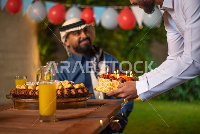 صورة مقربة لشاب يقوم بتقديم كيكة عيد الميلاد، مجموعة من الشباب العرب الخليجيين السعوديين يقضون أوقات ممتعة في إحدى الشاليهات السياحية بالسعودية، الاحتفال بعيد الميلاد، أعياد ومناسبات سعيدة، أجواء شتوية، جلسة وناسة وتعارف، إجتماع الأصدقاء، سهرة شبابية