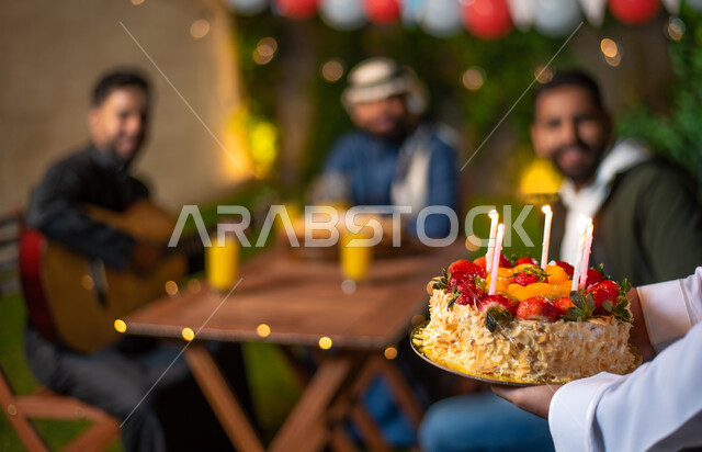 صورة مقربة لشاب يقوم بتقديم كيكة عيد الميلاد، مجموعة من الشباب العرب الخليجيين السعوديين يقضون أوقات ممتعة في إحدى الشاليهات السياحية بالسعودية، الاحتفال بعيد الميلاد، أعياد ومناسبات سعيدة، أجواء شتوية، جلسة وناسة وتعارف، إجتماع الأصدقاء، سهرة شبابية