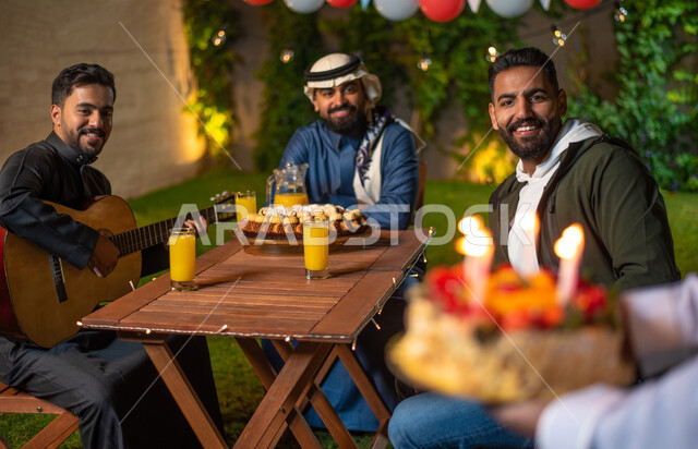 صورة مقربة لشاب يقوم بتقديم كيكة عيد الميلاد، مجموعة من الشباب العرب الخليجيين السعوديين يقضون أوقات ممتعة في إحدى الشاليهات السياحية بالسعودية، الاحتفال بعيد الميلاد، أعياد ومناسبات سعيدة، أجواء شتوية، جلسة وناسة وتعارف، إجتماع الأصدقاء، سهرة شبابية