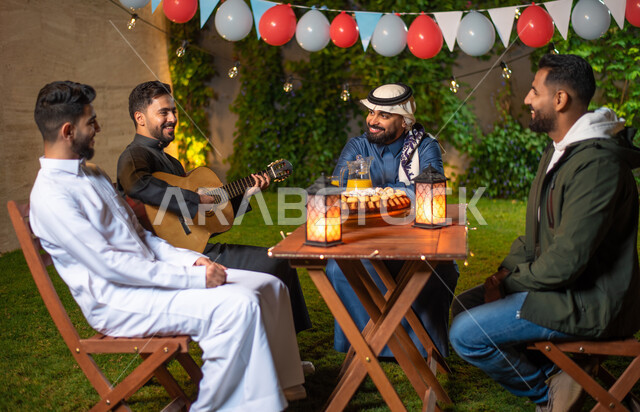 مجموعة من الشباب العرب الخليجيين السعوديين يقضون أوقات ممتعة في إحدى الشاليهات السياحية بالسعودية، فعاليات شبابية ترفيهية، شاب يعزف على آلة القيثارة، أجواء شتوية، جلسة وناسة وتعارف، إجتماع الأصدقاء، سهرة شبابية