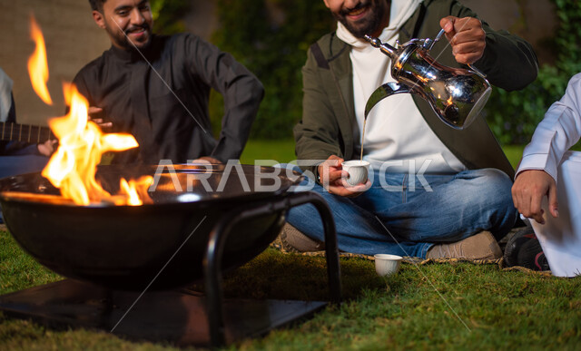 صورة مقربة لمجموعة من الشباب العرب الخليجيين السعوديين يقضون أوقات ممتعة في إحدى الشاليهات السياحية بالسعودية، فعاليات شبابية ترفيهية، شاب يقوم بصب القهوة، أجواء شتوية، أجواء شبابية سعيدة، جلسة وناسة وتعارف، إجتماع الأصدقاء، سهرة شبابية