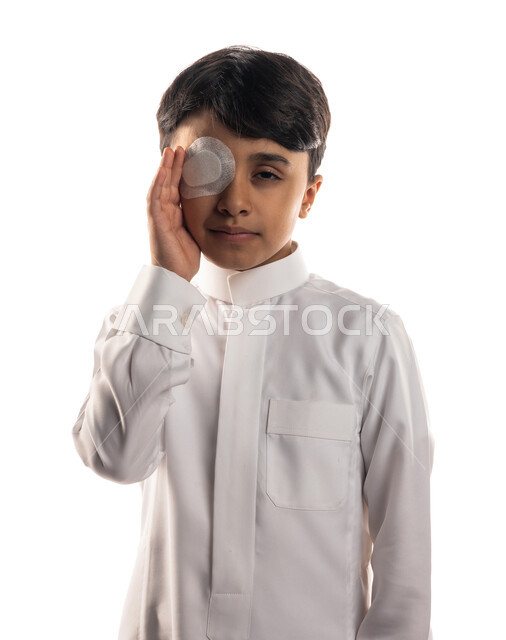 بورتريه لولد عربي سعودي خليجي ،  يضع ضمادة الجروح على عينه ، تغطية العين ، الإصابة بجرح في العين ، تعابير وجه تدل على الألم و الحزن ، خلفية بيضاء