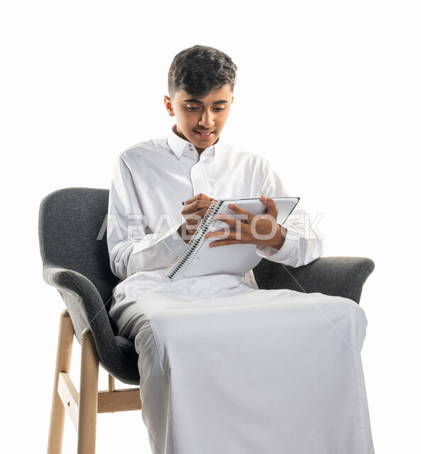 بورتريه لولد عربي سعودي خليجي، يجلس على كرسي، تأدية الواجبات المدرسية، مراجعة الدروس، الإستعداد للعام الدراسي الجديد، التعليم الدراسي في السعودية ، العودة إلى المدارس، المذاكرة للإختبارات المدرسية، خلفية بيضاء