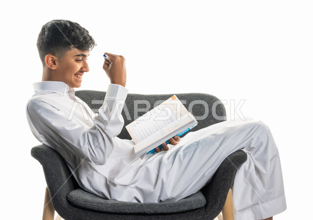 بورتريه لولد عربي سعودي خليجي، يجلس على كرسي، تعابير تدل على التفكير، تأدية الواجبات المدرسية، مراجعة الدروس، الإستعداد للعام الدراسي الجديد، التعليم الدراسي في السعودية ، العودة إلى المدارس، المذاكرة للإختبارات المدرسية، خلفية بيضاء