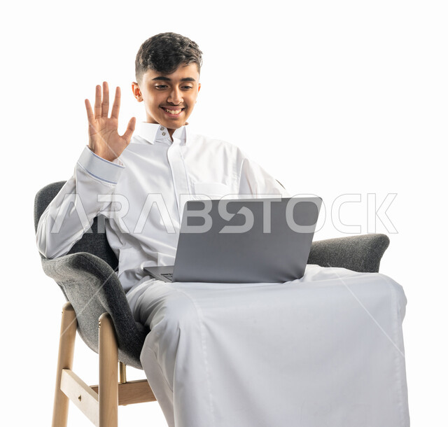 بورتريه لولد عربي سعودي خليجي ، يجلس على كرسي ،   إستخدام جهاز الحاسوب المحمول ، إجراء مكالمة فيديو ، بث مباشر ، التواصل مع الأصدقاء ، تصفح الإنترنت ، محادثات ودردشة ، التعليم الإلكتروني ، خلفية بيضاء