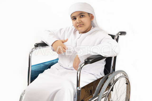 بورتريه لطفل عربي إماراتي خليجي يرتدي الزي التقليدي من ذوي الهمم يجلس على كرسي متحرك ويرتدي الزي التقليدي بإيماءات وجه مبتسمة  , التمكين الاجتماعي, اهتمام ودعم المجتمع الإماراتي لذوي الاحتياجات الخاصه, تقديم الحب و الرعاية و الاهتمام , خلفية بيضاء 