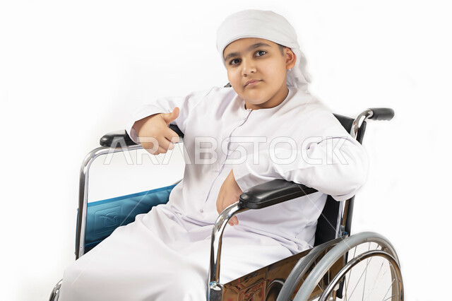بورتريه لطفل عربي إماراتي خليجي يرتدي الزي التقليدي من ذوي الهمم يجلس على كرسي متحرك ويرتدي الزي التقليدي بإيماءات وجه مبتسمة  , التمكين الاجتماعي, اهتمام ودعم المجتمع الإماراتي لذوي الاحتياجات الخاصه, تقديم الحب و الرعاية و الاهتمام , خلفية بيضاء 