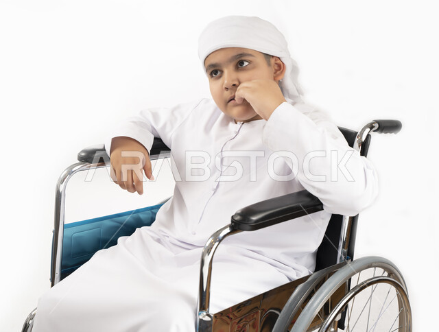 بورتريه لطفل عربي إماراتي خليجي يرتدي الزي التقليدي من ذوي الهمم يجلس على كرسي متحرك ويرتدي الزي التقليدي بإيماءات وجه مبتسمة  , التمكين الاجتماعي, اهتمام ودعم المجتمع الإماراتي لذوي الاحتياجات الخاصه, تقديم الحب و الرعاية و الاهتمام , خلفية بيضاء 