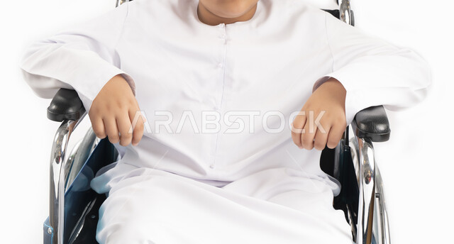 صورة مقربة لبورتريه لطفل عربي إماراتي خليجي يرتدي الزي التقليدي من ذوي الهمم يجلس على كرسي متحرك ويرتدي الزي التقليدي بإيماءات وجه مبتسمة  , التمكين الاجتماعي, اهتمام ودعم المجتمع الإماراتي لذوي الاحتياجات الخاصه, تقديم الحب و الرعاية و الاهتمام , خلفية ب