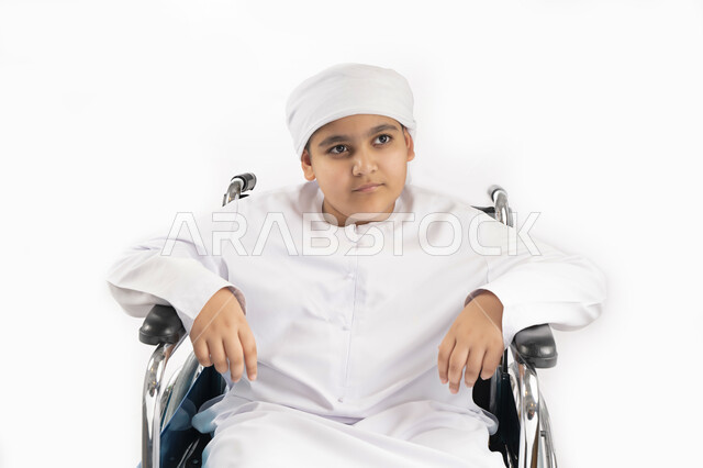 بورتريه لطفل عربي إماراتي خليجي يرتدي الزي التقليدي من ذوي الهمم يجلس على كرسي متحرك ويرتدي الزي التقليدي بإيماءات وجه مبتسمة  , التمكين الاجتماعي, اهتمام ودعم المجتمع الإماراتي لذوي الاحتياجات الخاصه, تقديم الحب و الرعاية و الاهتمام , خلفية بيضاء 