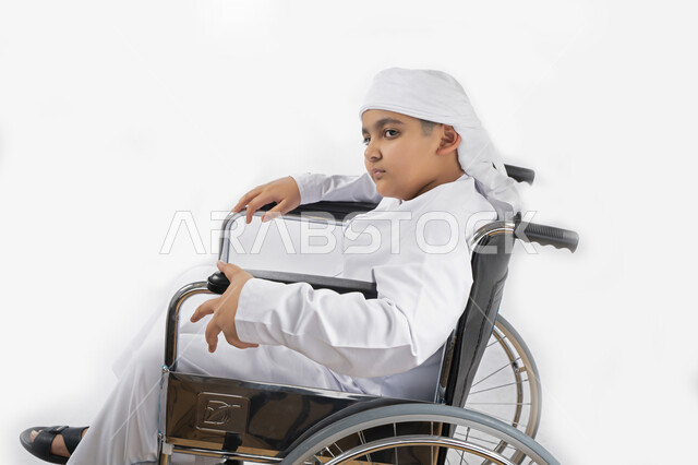 بورتريه لطفل عربي إماراتي خليجي يرتدي الزي التقليدي من ذوي الهمم يجلس على كرسي متحرك ويرتدي الزي التقليدي بإيماءات وجه مبتسمة  , التمكين الاجتماعي, اهتمام ودعم المجتمع الإماراتي لذوي الاحتياجات الخاصه, تقديم الحب و الرعاية و الاهتمام , خلفية بيضاء 