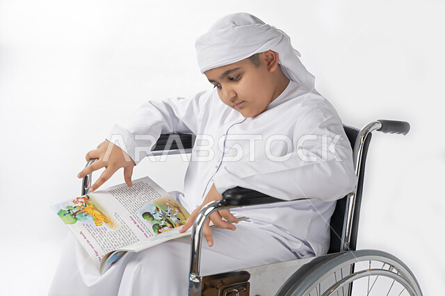 بورتريه لطفل عربي إماراتي خليجي يرتدي الزي التقليدي من ذوي الهمم يجلس على كرسي متحرك يؤدي فروضه المدرسية  , التمكين الاجتماعي, اهتمام ودعم المجتمع الإماراتي لذوي الاحتياجات الخاصه, التعليم المنزلي , تعليم عن بعد , خلفية بيضاء 