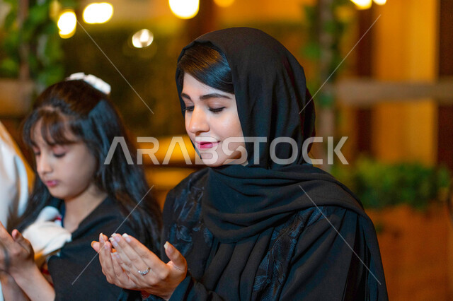 أجواء وعبادات دينية إسلامية, سحور رمضاني عائلي, صورة مقربة لأم عربية خليجية إمارتية وابنتها تجلسان على سفرة الطعام وتدعوان الله عند موعد الإفطار, أم سعودية وابنتها تشكران الله بعد تناول الغداء, الدعاء المستجاب وقت أذان المغرب, اسلاميات وروحانيات رمضانية