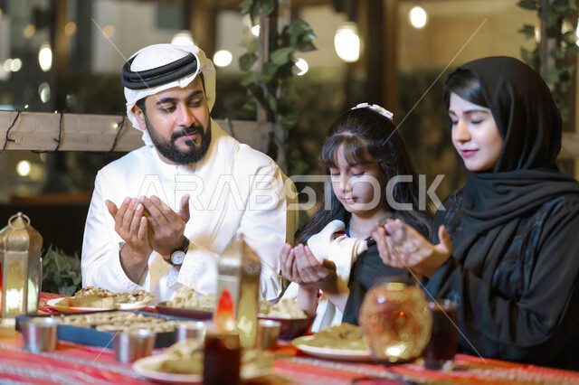  أسرة سعودية تستعد لتناول الطعام المطعم، سفرة إفطار مليئة بأصناف من المأكولات والمقبلات الشهية، اسلاميات وعبادات رمضانية, عائلة عربية خليجية إماراتية تجلس على مائدة الطعام وتدعو الله عند موعد الإفطار في شهر رمضان المبارك, فضل الدعاء وقت أذان المغرب.
