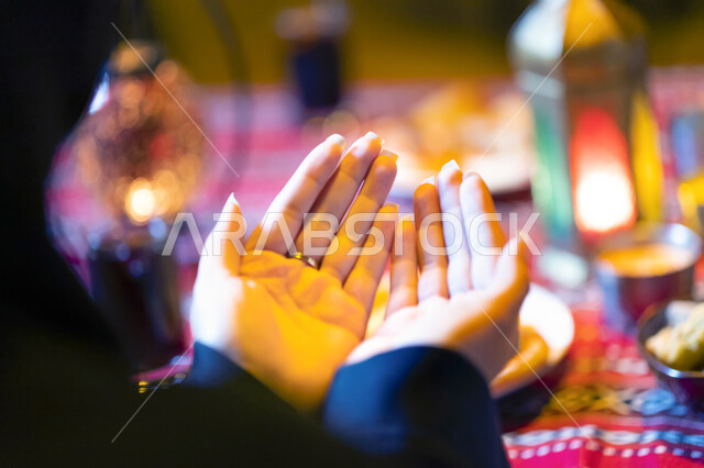  إسلاميات وعبادة، ايماءات يد تدل على الدعاء و التقرب من الله، الجلوس على مائدة رمضان وشكر الله بعد تناول الطعام، الدعاء المستجاب وقت آذان المغرب، صورة من الخلف لإمرأة عربية خليجية إماراتية تستعد للإفطار، إمرأة سعودية ترفع يديها وتدعو الله تعالى. 