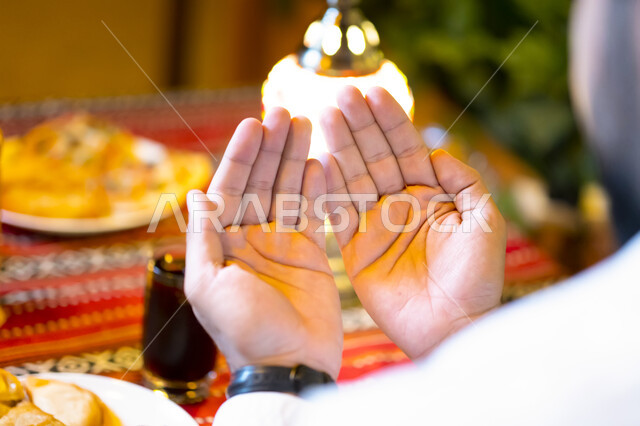 ايماءات يد تدل على الدعاء والتقرب إلى الله سبحانه وتعالى, الجلوس على مائدة رمضان وشكر الله بعد تناول الطعام, الدعاء المستجاب وقت أذان المغرب, صورة من الخلف لرجل عربي خليجي إماراتي يستعد للإفطار, رجل سعودي يرفع يديه ويدعو الله تعالى, إسلاميات وعبادة