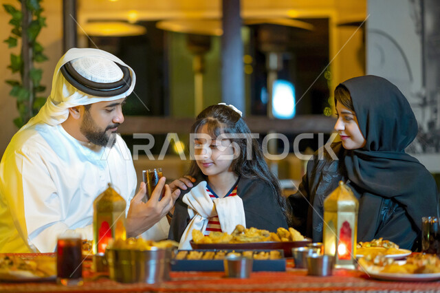 A religious family atmosphere, the family gathers on a luxurious Ramadan trip abroad, a dining table full of varieties of delicious food and appetizers, a close-up of an Emirati Arab family enjoying breakfast in the blessed month of Ramadan, a Saudi famil