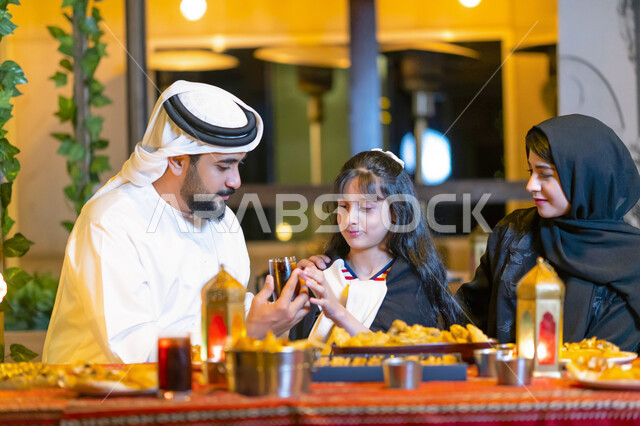 The family gathered on a luxurious Ramadan trip abroad, a dining table filled with varieties of delicious food and appetizers, a close-up of an Emirati Arab family enjoying breakfast in the blessed month of Ramadan, a Saudi family sitting in a restaurant 