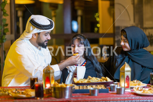 A religious family atmosphere, family meeting and sharing food at a suhoor table filled with varieties of delicious food and appetizers, a close-up of an Emirati Arab family sitting on the Ramadan Iftar meal, a Saudi family enjoying Ramadan breakfast outs