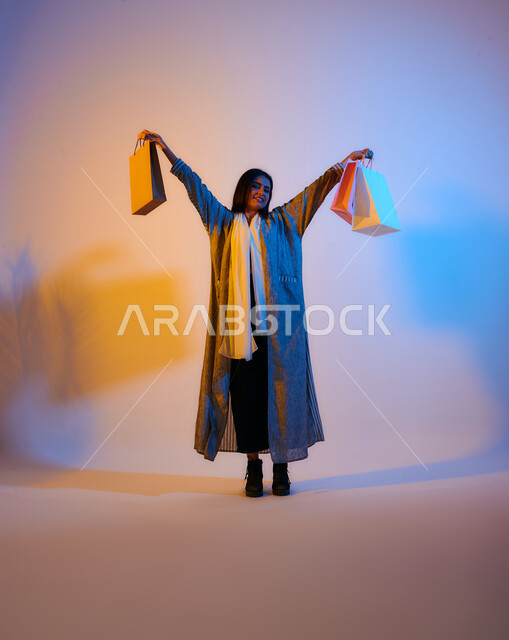 Portrait of a Saudi Arabian Gulf woman wearing an elegant colorful abaya carrying shopping bags in her hand, online shopping, international brands, shopping in malls, the fun of shopping in Saudi Arabia, colorful shopping bags, seasonal offers and discoun