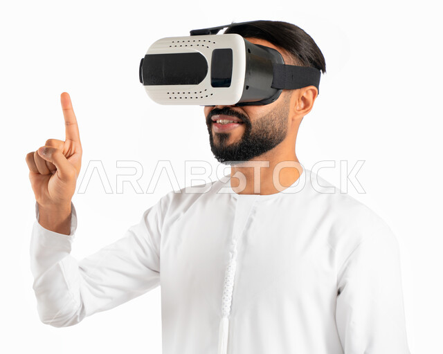 الضغط والنقر وإستخدام حاسة اللمس، بورتريه لرجل إماراتي عربي خليجي يرتدي الكندورة الإماراتية ونظارات في آر ثلاثية الإبعاد ويشير بأصبع السبابة لشئ ما يشاهده بالواقع الإفتراضي، محاكاة العالم الافتراضي، حركة اصبع وإشارات، خلفية بيضاء