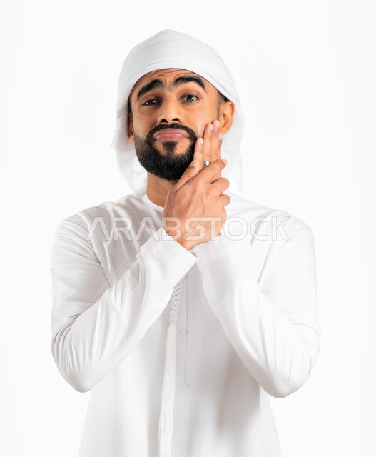 The need to visit the dentist, a portrait of a Gulf Arab Emirati man wearing a turban and an Emirati kandora and placing his hand on his face. Face and hand gestures indicate pain and mouth pain, gingivitis and tooth decay, fatigue, exhaustion and swollen