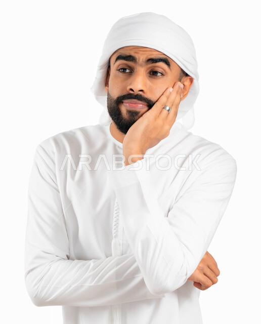 التمعن والتأمل في موضوع ما، بورتريه لرجل إماراتي خليجي عربي يرتدي الكندورة والعمامة الإماراتية ويضع يده على ذقنه، إيماءات الملل واللامبالاة، التفكير والحيرة والتركيز في حل المشكلات، خلفية بيضاء