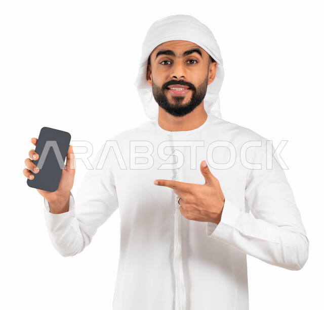 E-marketing and displaying mobile services and applications, a portrait of an Arab Gulf Emirati man wearing a kandora and an Emirati turban and pointing his index finger at a mobile phone with a blank black screen, using smartphone software, a white backg