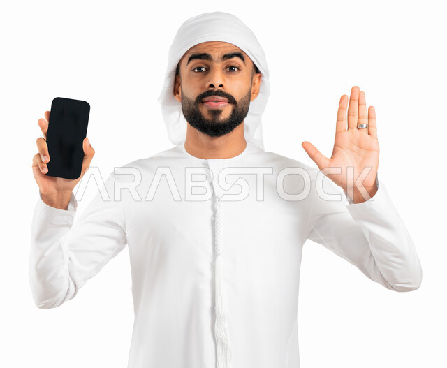 التسويق الإلكتروني بإستخدام برامج الهاتف الذكي، بورتريه لرجل خليجي إماراتي عربي يرتدي الكندورة والعمامة الإماراتية ويقوم بعرض الهاتف المحمول بشاشة سوداء فارغة، إيماءات يد تدل على التوقف ومنع الإستخدام السيء للهاتف المحمول، خلفية بيضاء