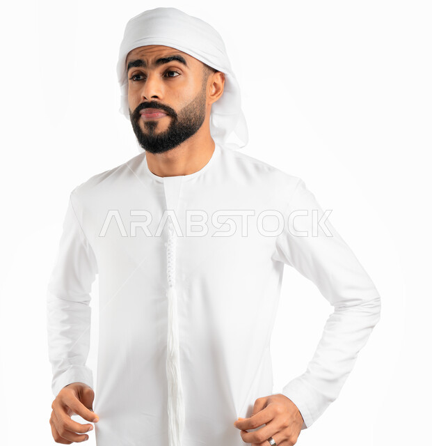 الإمساك بالكندورة والنظر إلى الكاميرا، الزي الإماراتي الشعبي، بورتريه لرجل عربي خليجي إماراتي يرتدي العمامة الإماراتية والكندورة، الوقوف بإستقامة وثقة، خلفية خضراء