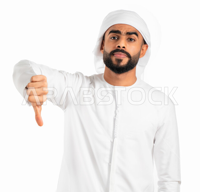Dislike and non-acceptance of something, negative evaluation and failure, portrait of an Arab Emirati man wearing a kandura and an Emirati turban, thumbs down gestures indicating rejection, resentment and dissatisfaction, finger movement and gestures, whi