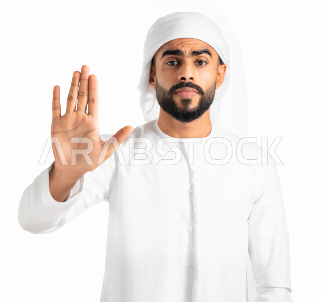إيماءات عدم القبول ورفض فعل شيء ما، بورتريه لرجل عربي خليجي إماراتي يرتدي الكندورة والعمامة الإماراتية ويرفع يده لأعلى بإشارة قف، طلب التوقف والإمتناع عن أمر ما، حركة يد وإشارات، خلفية بيضاء