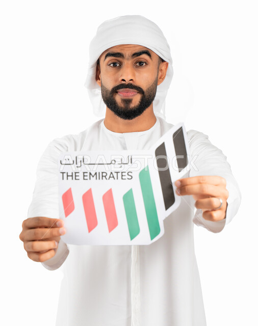 إمساك شعار على شكل خريطة الإمارات العربية المتحدة ملون بألوان العلم الإماراتي، بورتريه لرجل إماراتي عربي خليجي يرتدي الكندورة والعمامة الإماراتية، إحياء ذكرى يوم توحيد الولايات وإستقلال الإمارات، الإحتفال بالعيد الوطني الإماراتي، خلفية بيضاء
