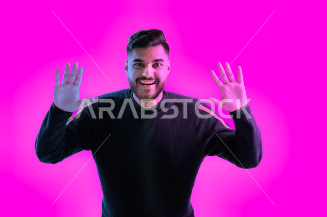 Feeling happy and joyful to carry out the required duties, facial and hand gestures indicating the completion of something, a close-up portrait of a smiling Emirati Arab man raising his hands up looking at the camera, the concept of elegance and fashion, 