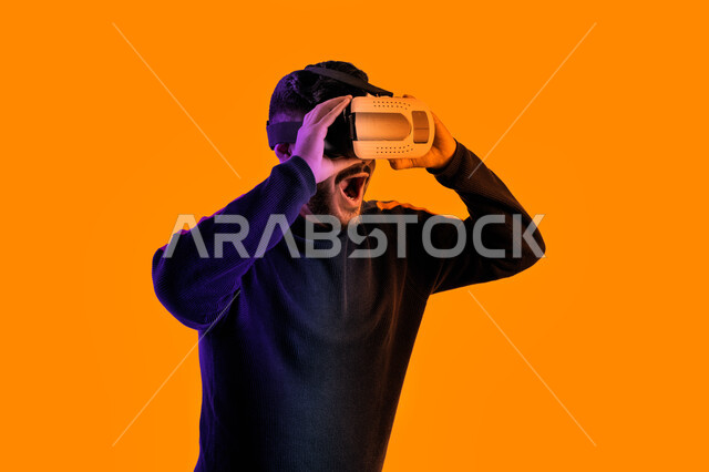 Watching movies through VR glasses, a close-up portrait of a Saudi Arab Gulf man wearing casual clothes and 3D virtual reality glasses, an Emirati young man interacting with the film and simulating the imaginary world, face and hand gestures indicating su