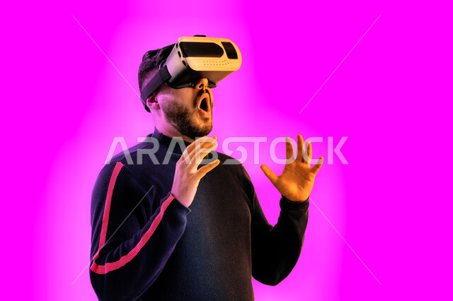 Simulation of the imaginary world and interaction with the film, face and hand gestures indicating astonishment and astonishment, an Emirati young man watching movies through virtual reality glasses, a close-up portrait of a Saudi Arabian Gulf man wearing
