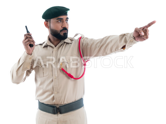 تأمين المنشأت وحماية الأفراد، إدارة الأزمات والكوراث، استخدام جهاز الإرسال والإستقبال اللاسلكي، بورتريه لشرطي عربي خليجي إماراتي يرتدي الزي العسكري ويشير بإصبع السبابة نحو شيء ما، حركة إصبع وإشارات، الحفاظ الأمن والأمان والطمأنينة، خلفية بيضاء