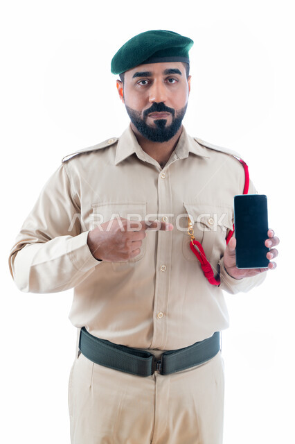 برامج وانظمة حماية الهاتف المحمول، بورتريه لشرطي عربي إماراتي خليجي يرتدي بدلة الشرطة الرسمية ويشير بإصبع السبابة نحو الجوال بشاشة سوداء فارغة، إستخدام تطبيقات الأمن والسلامة في الهاتف الذكي، خلفية بيضاء