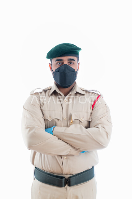 جمع الأدلة للتحقق والتحري في موقع الجريمة، إيماءات يدين تدل على الثقة، بورتريه لمحقق جنائي عربي خليجي إماراتي يرتدي الكمامة الواقية والقفازات وبدلة الشرطة الرسمية ويقف بإستقامة وإنضباط، البحث لكشف حقائق الجرائم، خلفية بيضاء