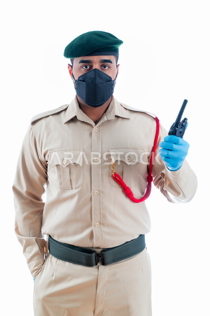 Communicating with the research team at the crime scene, a portrait of an Emirati Arab Gulf criminal investigator wearing a police uniform and using a wireless transmitter and receiver, securing facilities and protecting individuals, enhancing security, s