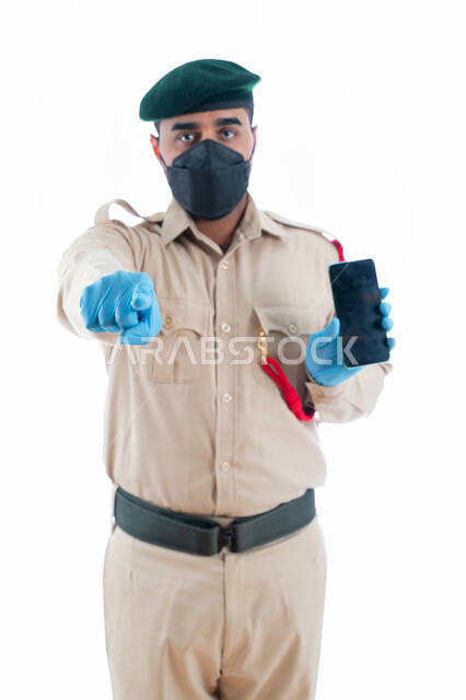 برامج وانظمة حماية الهاتف المحمول، الجوال بشاشة سوداء فارغة، بورتريه لمحقق أدلة جنائية عربي خليجي إماراتي يرتدي الكمامة الواقية والقفازات وبدلة الشرطة الرسمية ويشير بإصبع السبابة نحو شيء ما، إستخدام تطبيقات الأمن والسلامة في الهاتف الذكي، خلفية بيضاء