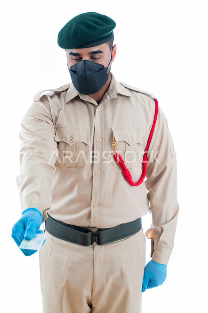 التأكد من المعلومات الشخصية للأشخاص في موقع الجريمة، بورتريه لشرطي عربي خليجي إماراتي يرتدي زي شرطة دبي ويمسك بيده بطاقة الهوية والمعلومات الشخصية لتفادي انتحال الشخصية، ارتداء الكمامة الواقية والقفازات، خلفية بيضاء