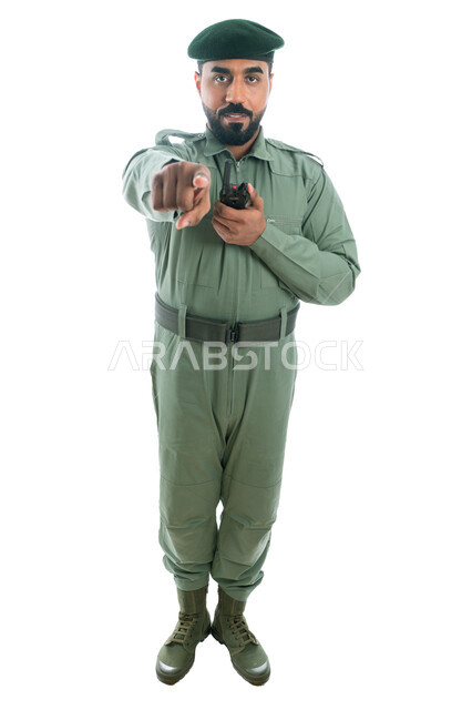 تأمين المنشأت وحماية الأفراد، الإشارة بإصبع السبابة نحو شيء ما، بورتريه لرجل أمن عربي خليجي إماراتي يرتدي بدلة الأمن الخضراء ويستخدم جهاز الإرسال والإستقبال اللاسلكي، حركة إصبع وإشارات، صورة الجسم بالطول الكامل، خلفية بيضاء