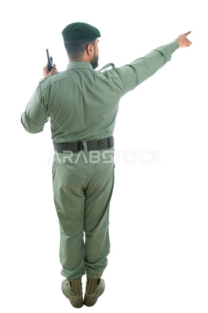 الإستجابة لحالات الطوارئ، الإشارة بإصبع السبابة نحو شيء ما، بورتريه من الخلف لرجل أمن عربي خليجي إماراتي يرتدي بدلة الأمن الخضراء ويستخدم جهاز الإرسال والإستقبال اللاسلكي، حركة إصبع وإشارات، صورة الجسم بالطول الكامل، خلفية بيضاء