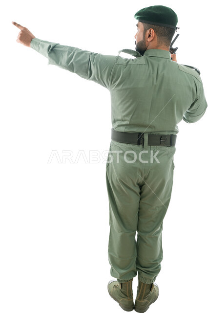 تعزيز الأمن والأمان والثقة بالشرطة، بورتريه من الخلف لرجل أمن خليجي عربي إماراتي يرتدي بدلة الأمن الخضراء ويستخدم جهاز الإرسال والإستقبال اللاسلكي، الإشارة بإصبع السبابة نحو شيء ما، حركة إصبع وإشارات، صورة الجسم بالطول الكامل، خلفية بيضاء